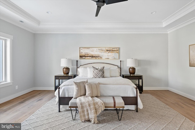 bedroom with crown molding, a tray ceiling, ceiling fan, and light hardwood / wood-style floors