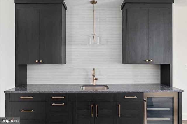 bar with wine cooler, hanging light fixtures, decorative backsplash, and a sink