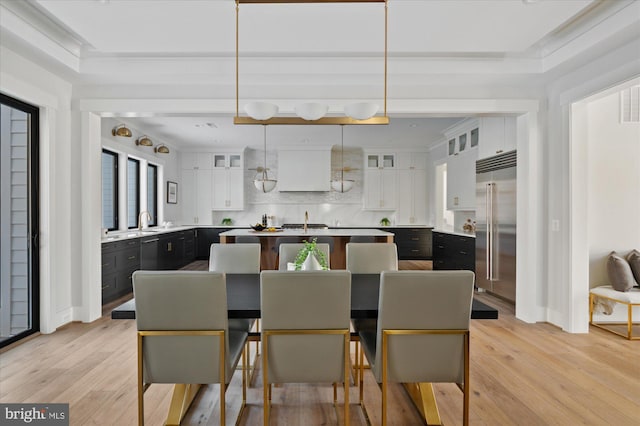 dining space with crown molding, sink, and light wood-type flooring