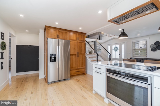 kitchen with light hardwood / wood-style flooring, appliances with stainless steel finishes, white cabinetry, decorative light fixtures, and french doors