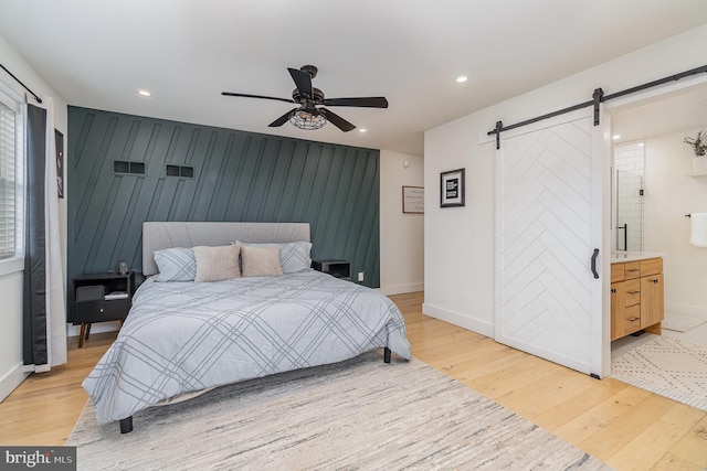 bedroom featuring ceiling fan, a barn door, and light hardwood / wood-style floors