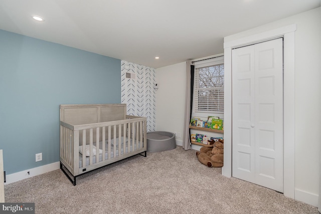 carpeted bedroom featuring a nursery area and a closet