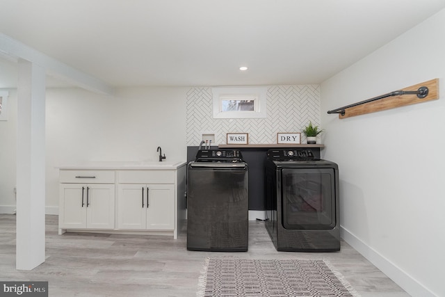 laundry room featuring cabinets, separate washer and dryer, sink, and light wood-type flooring