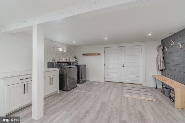 laundry area featuring cabinets, washer and dryer, and light hardwood / wood-style flooring