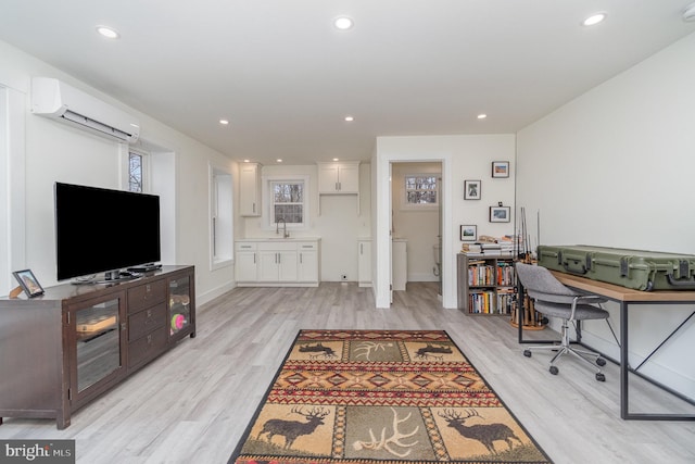 office featuring sink, light hardwood / wood-style floors, and a wall mounted AC