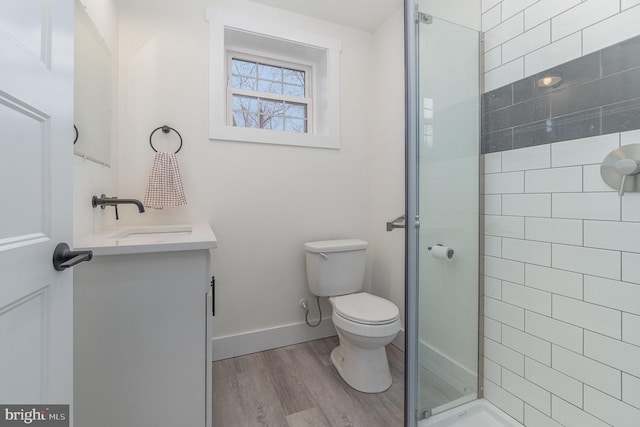 bathroom featuring vanity, hardwood / wood-style floors, a shower with shower door, and toilet