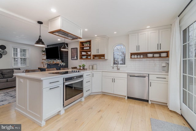 kitchen with sink, decorative light fixtures, stainless steel appliances, and white cabinets