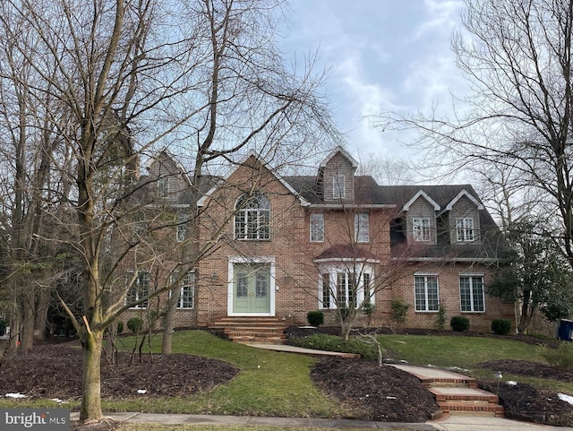 view of front facade featuring a front yard, brick siding, and entry steps