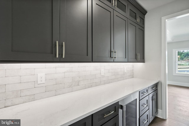 kitchen featuring wine cooler, backsplash, light hardwood / wood-style floors, and light stone counters