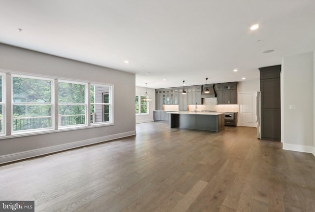 unfurnished living room featuring dark hardwood / wood-style flooring, sink, and a notable chandelier