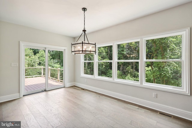 unfurnished dining area featuring wood-type flooring and a chandelier