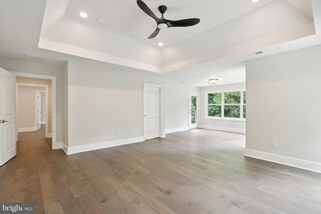 spare room with hardwood / wood-style floors, a raised ceiling, and ceiling fan