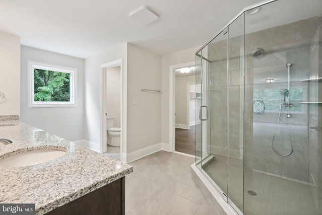 bathroom with tile patterned flooring, vanity, a shower with shower door, and toilet