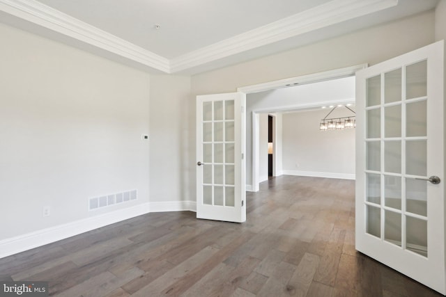 unfurnished room with ornamental molding, hardwood / wood-style floors, an inviting chandelier, and french doors