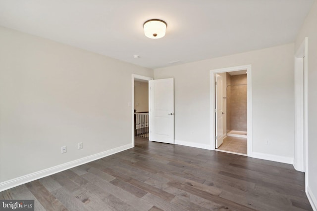 unfurnished bedroom featuring dark hardwood / wood-style floors and ensuite bath