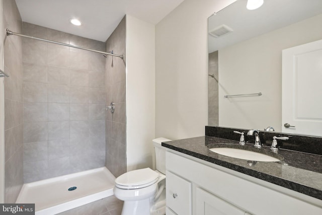 bathroom with tile patterned flooring, vanity, tiled shower, and toilet