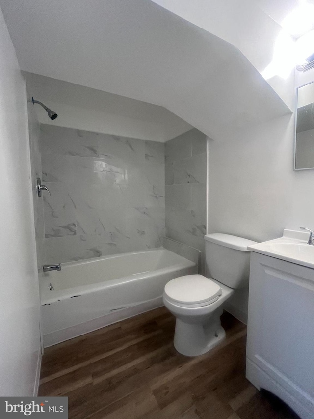 full bathroom with hardwood / wood-style flooring, vanity, tiled shower / bath combo, and toilet