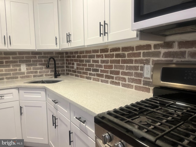 kitchen featuring white cabinetry, sink, light stone counters, and appliances with stainless steel finishes