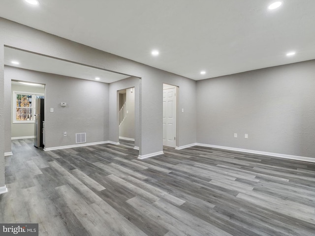 basement with dark hardwood / wood-style floors and stainless steel refrigerator