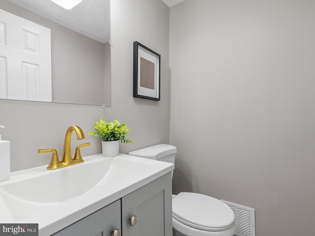 bathroom featuring vanity, a textured ceiling, and toilet