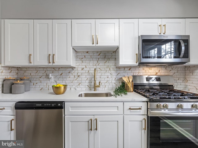 kitchen with sink, white cabinets, stainless steel appliances, light stone countertops, and backsplash