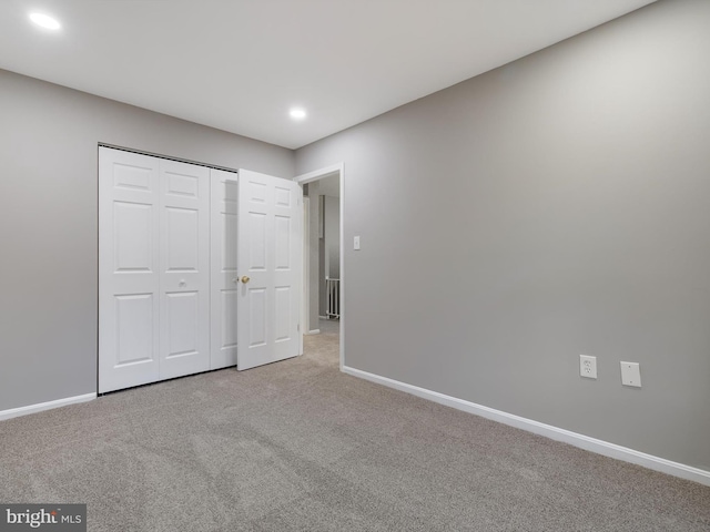 unfurnished bedroom featuring light carpet and a closet