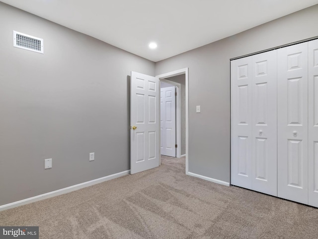 unfurnished bedroom featuring light carpet and a closet