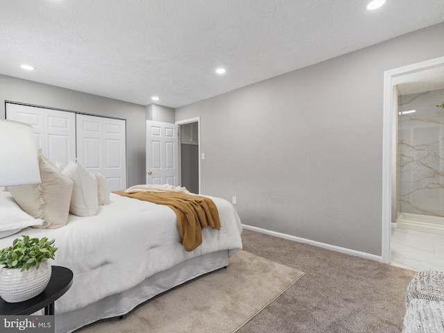 bedroom with ensuite bathroom, carpet floors, a textured ceiling, and a closet