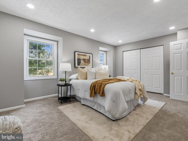 bedroom with a closet, light carpet, and a textured ceiling