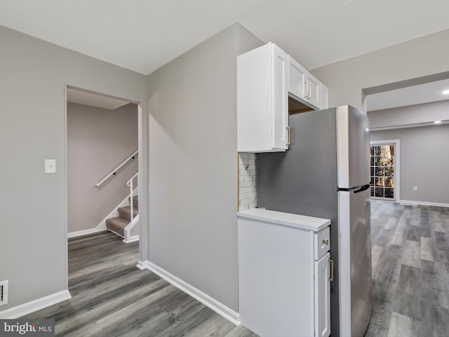 kitchen with tasteful backsplash, hardwood / wood-style floors, stainless steel refrigerator, and white cabinets