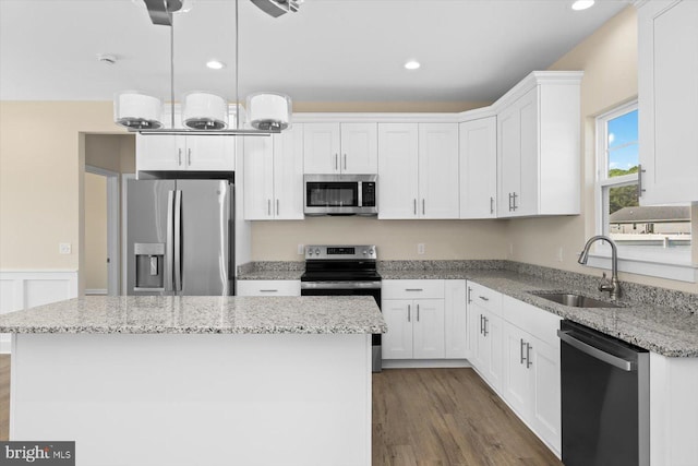 kitchen featuring appliances with stainless steel finishes, dark wood-type flooring, white cabinets, a sink, and a kitchen island