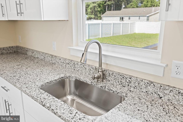 details featuring light stone countertops, white cabinets, and a sink