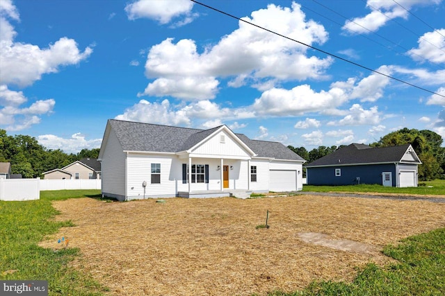 view of front of property featuring a garage, covered porch, fence, and a front yard