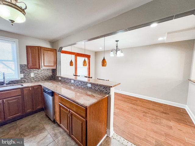 kitchen with decorative light fixtures, tasteful backsplash, sink, stainless steel dishwasher, and kitchen peninsula