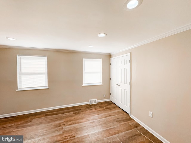 spare room with crown molding and wood-type flooring