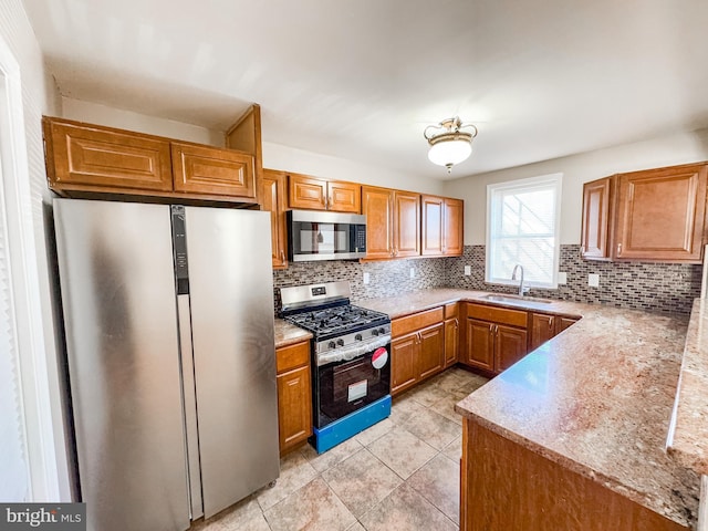 kitchen with sink, light stone counters, light tile patterned floors, stainless steel appliances, and decorative backsplash