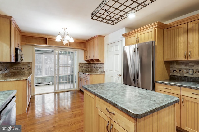 kitchen with light hardwood / wood-style flooring, baseboard heating, stainless steel appliances, a kitchen island, and decorative backsplash