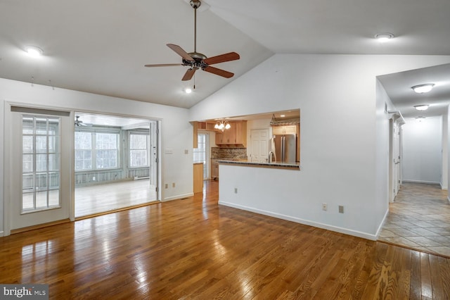 unfurnished living room featuring high vaulted ceiling, light hardwood / wood-style floors, and ceiling fan