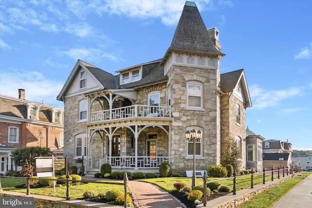 view of front of property with a porch, a balcony, and a front yard