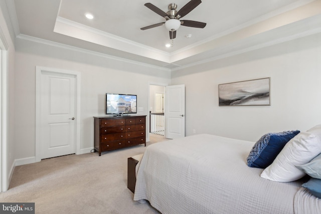 bedroom featuring a raised ceiling, ornamental molding, light colored carpet, and ceiling fan