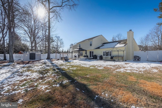 snow covered property with a gazebo and a storage unit