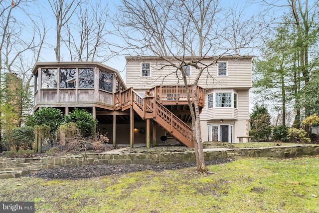 rear view of house featuring a wooden deck, a sunroom, and a yard