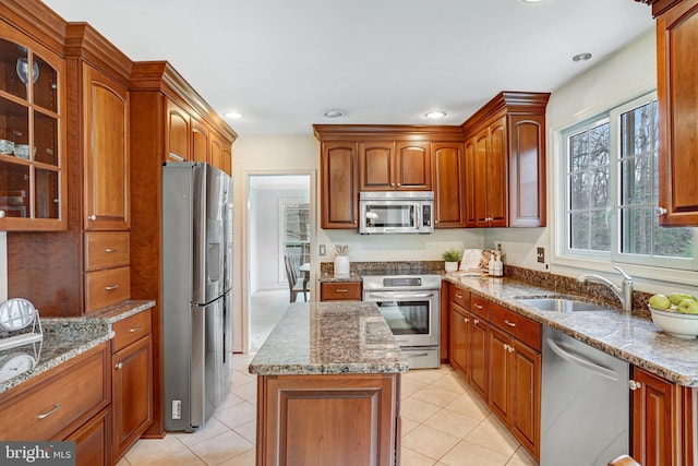 kitchen featuring stainless steel appliances, sink, light tile patterned floors, and light stone counters