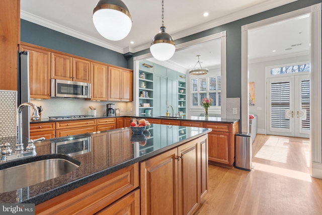 kitchen featuring decorative light fixtures, sink, dark stone counters, stainless steel appliances, and crown molding