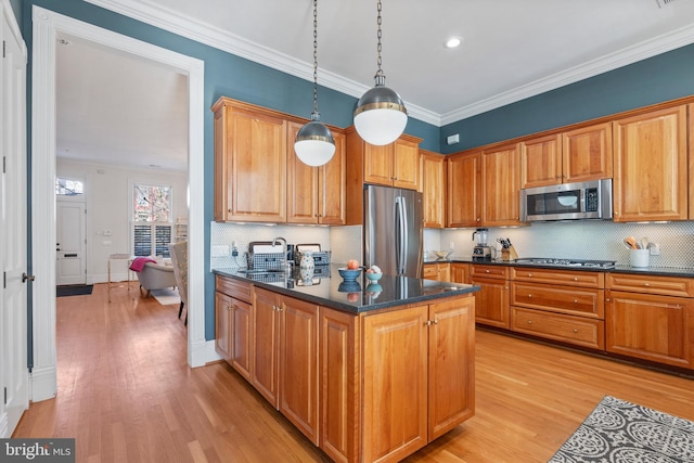 kitchen featuring stainless steel appliances, crown molding, sink, and pendant lighting