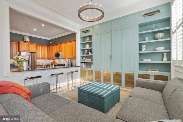 living room with ornamental molding, sink, a notable chandelier, and built in shelves