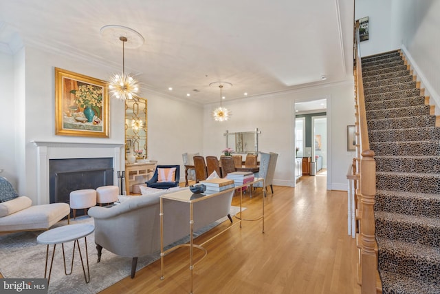 living room with ornamental molding, a chandelier, and light wood-type flooring