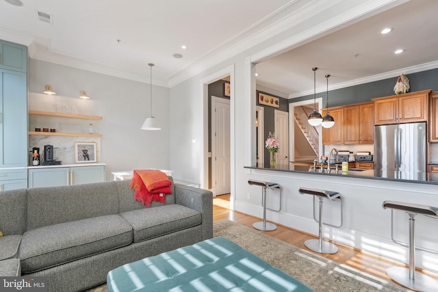 living room featuring sink, crown molding, and light hardwood / wood-style flooring