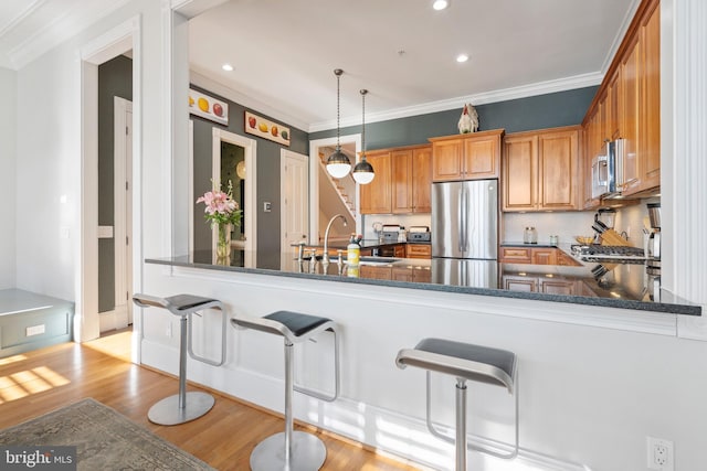 kitchen featuring pendant lighting, stainless steel appliances, kitchen peninsula, and sink