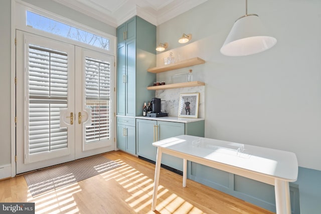 kitchen featuring french doors, ornamental molding, light hardwood / wood-style floors, and hanging light fixtures